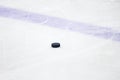 Old , black ice hockey puck near blue line in ice hockey rink Royalty Free Stock Photo