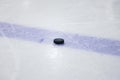 Old , black ice hockey puck near blue line in ice hockey rink Royalty Free Stock Photo