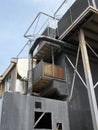 Old black industrial building with rusting steel girders tanks and pipes and railings against a blue sky Royalty Free Stock Photo