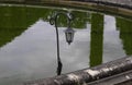 Old black iron street lantern in the park against the background of reflections in the water Royalty Free Stock Photo