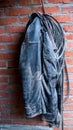 Old black leather jacket hanging on a hook on a brick wall, copy space