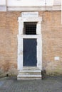 Old black metal iron door with white stone marble frame portal in red brick wall Royalty Free Stock Photo