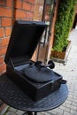 Old black mockup vintage gramophone on the metal table on the background of red brick wall. Outdoors. Vertical. Urbal