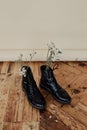 Old black mountain boots used as flower pots on the old wooden floor Royalty Free Stock Photo