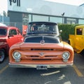 Old black and orange 1956 Ford F 100 V8 pickup truck in a parking lot at a classic car show Royalty Free Stock Photo