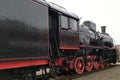 Old black and red retro steam locomotive at the railway station. Vintage train staying on the railroad.