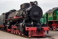 Old black and red retro steam locomotive at the railway station. Vintage train staying on the railroad. Royalty Free Stock Photo