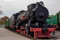 Old black and red retro steam locomotive at the railway station. Vintage train staying on the railroad.