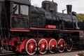 Old black and red retro steam locomotive at the railway station. Vintage train staying on the railroad. Royalty Free Stock Photo