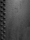 Old black rough iron metal surface with grainy texture and lines of rivets Royalty Free Stock Photo