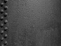 Old black rough iron metal surface with grainy texture and lines of rivets Royalty Free Stock Photo