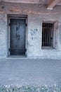 Old black rusty metal door and window with steel grids