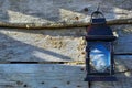 Old black shabby lamp hanging on a rustic wooden wall of a barn