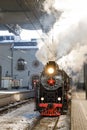 Old black steam locomotive in Russia in the winter on the background of the Moscow railway station Royalty Free Stock Photo