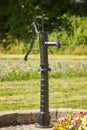 Old black street water pump. Usually the water from such pumps is not potable. In the background street and buildings painted in d Royalty Free Stock Photo