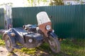 An old black Ural motorcycle with a sidecar is parked on the side of the road near the fence.