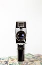 The old black video camera is on the US dollar banknotes and there is a white background behind it. Video creator and money Royalty Free Stock Photo
