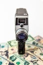 The old black video camera is on the US dollar banknotes and there is a white background behind it. Video creator and money Royalty Free Stock Photo