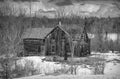 Old black and white abandoned spooky looking farmhouse in winter on a farm yard in rural Canada