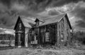 Old black and white abandoned spooky looking farmhouse in winter on a farm yard in rural Canada Royalty Free Stock Photo