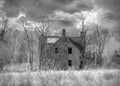 Old black and white abandoned spooky looking farmhouse in winter on a farm yard in rural Canada Royalty Free Stock Photo