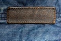 Old blank leather label on blue denim cloth - close-up with selective focus. long tag Royalty Free Stock Photo