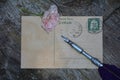 Old blank vintage postcard with old stamp is on old wood with pink rose and nib Royalty Free Stock Photo