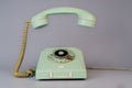 Old blue aged rotary telephone with removed hanging receiver on grey background. Vintage landline home phone with dial Royalty Free Stock Photo