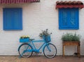 Old blue bicycle stands on the street near the wall with windows with wooden shutters Royalty Free Stock Photo