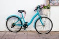 An old blue bike with flat tyres and flowers in the basket leaning against a white wall Royalty Free Stock Photo