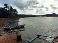 Blue boats on the shore surrounded by green palm trees under a cloudy sky Royalty Free Stock Photo