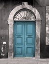 Old blue door in an arched stone frame with flaking back painted walls Royalty Free Stock Photo