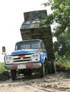 Old blue dump truck is dumping soil