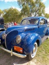 Old blue 1938 Ford V8 85 De Luxe coupe in a park. Classic car show.