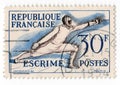 An old blue french postage stamp with an image of a man in a sword fencing costume Royalty Free Stock Photo