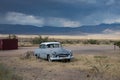 Old blue-gray 1954 Chrysler Windsor with a white top abandoned on a desert road