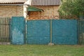 Old blue iron gate and a closed metal door on a wooden fence Royalty Free Stock Photo