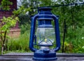 Old blue kerosene lantern, with a burning wick on an old worn wooden table Royalty Free Stock Photo