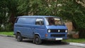 An old blue minibus is parked near the lawn