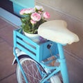 Old blue retro bike with flowers in a basket near the store. Decorative stylish arrangement of the store