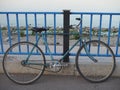 Old blue retro bike with rust places chained lock to the bars on the waterfront Royalty Free Stock Photo