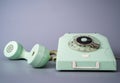 Old blue rotary telephone with twisted cord on gray background. Retro landline phone with rotary dialer and remote Royalty Free Stock Photo