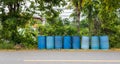 Old blue round plastic bins lined up on the side of the road Royalty Free Stock Photo