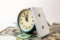 An old blue ruined analog clock that shows five minutes to twelve o`clock. The watch is on US dollar bills, and next to it is a Royalty Free Stock Photo