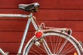 An old, blue and rusty bicycle leaning against a red, wooden wall Royalty Free Stock Photo