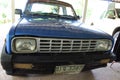 An old blue small pickup truck parked in the garage in front of the house.