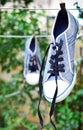 Old blue sneaker hanging on a rope behind a wooden clothespin Royalty Free Stock Photo