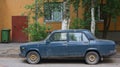 An old blue Soviet car in the courtyard of a residential building