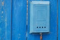 An old blue Soviet mailbox with an inscription and a rusty lock hanging on a rural wooden blue fence Royalty Free Stock Photo