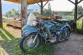 The old blue Soviet retro motorcycle with sidecar parked in the countryside